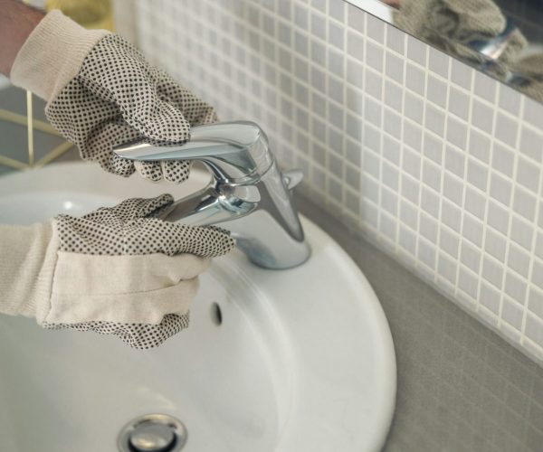 Close up of plumber is repairing faucet of a sink at bathroom. Good quality plumbing company service