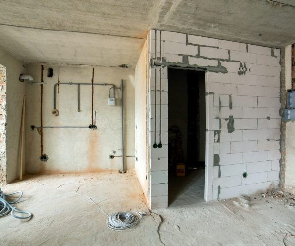 Interior of an apartment room with bare walls and ceiling under construction